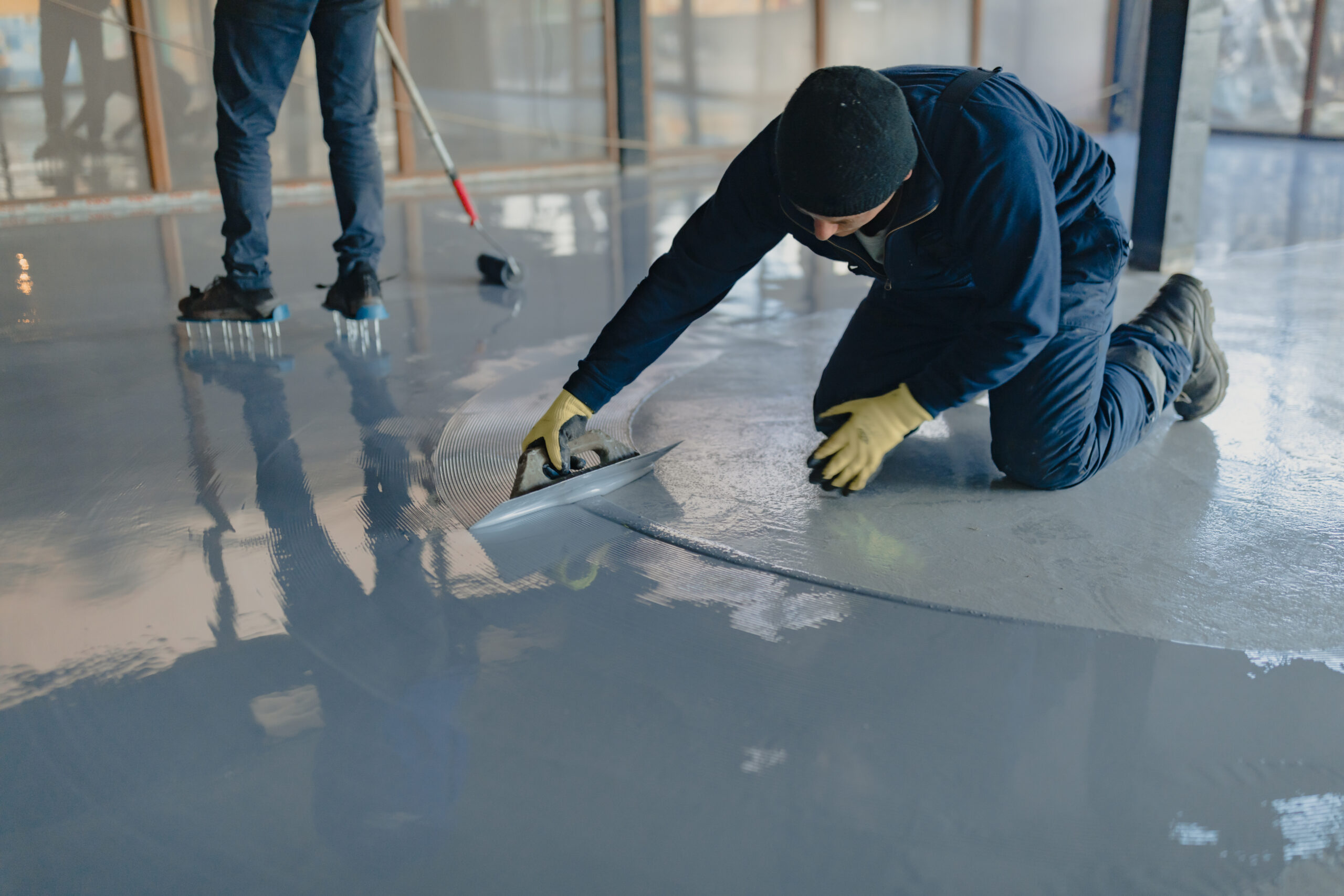 The worker applies gray epoxy resin to the new floor The worker applies gray epoxy resin to the new floor